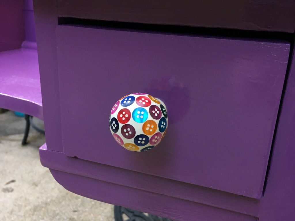 Closeup of knob with colorful buttons embedded in resin.